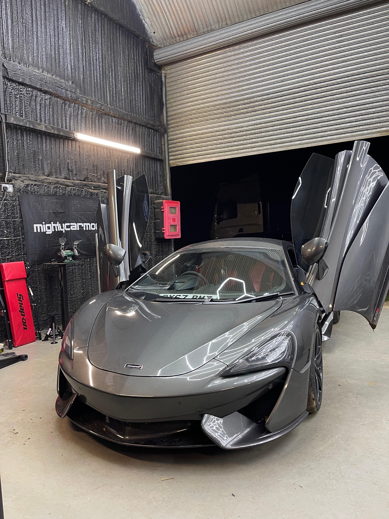 Grey McLaren 570S in the workshop with both doors raised