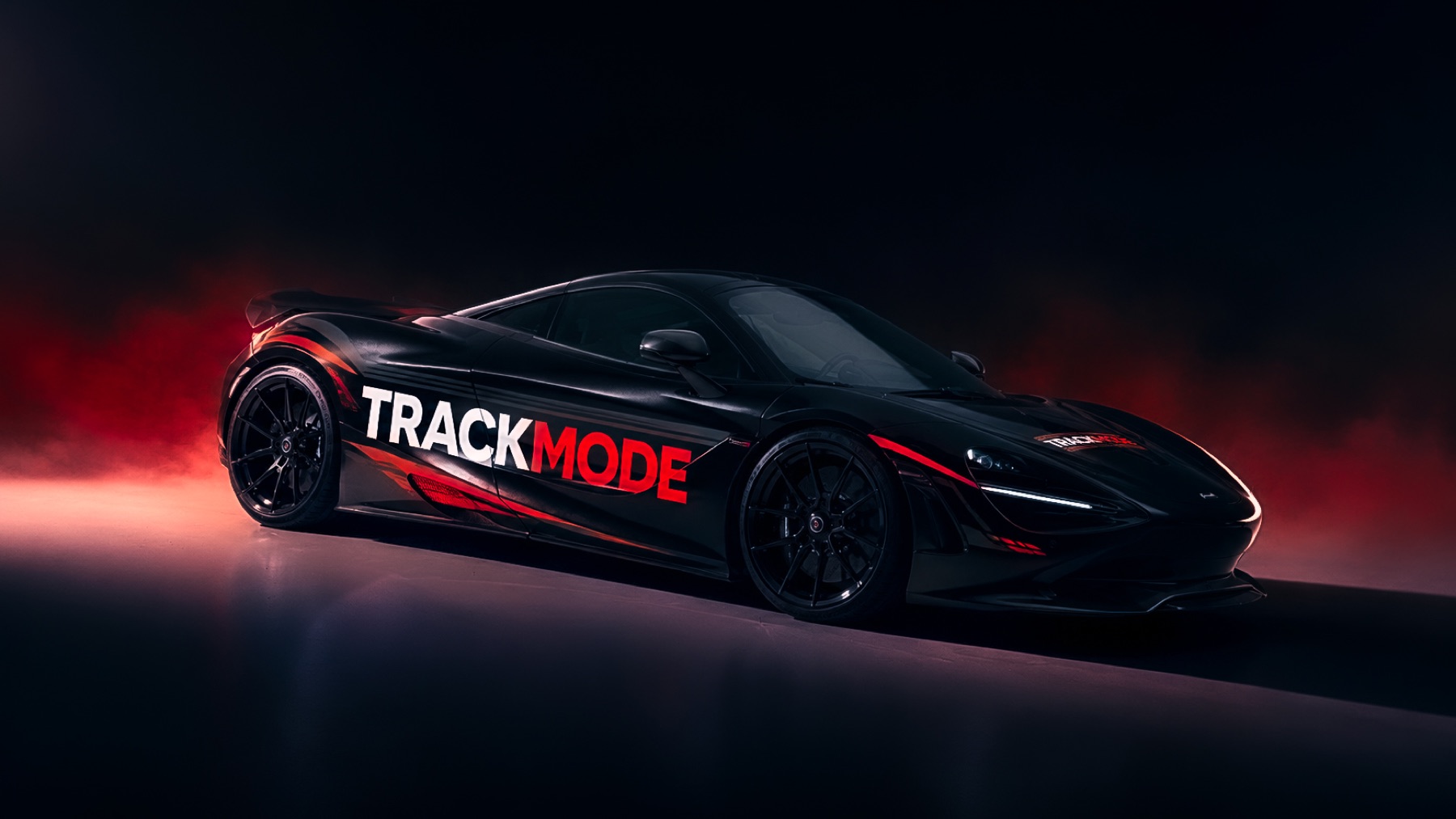 Black McLaren with TRACKMODE side graphics under red lighting